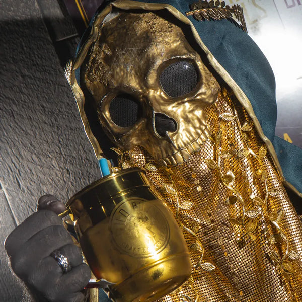Costumed fan holding a gold Wild Bill's mug at a convention.